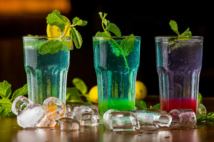 three glasses filled with different colored drinks